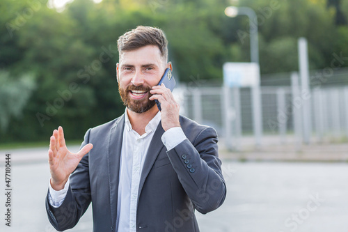 Portrait of a happy bearded businessman, close-up photo of a man looking at the camera smiling and talking on the phone