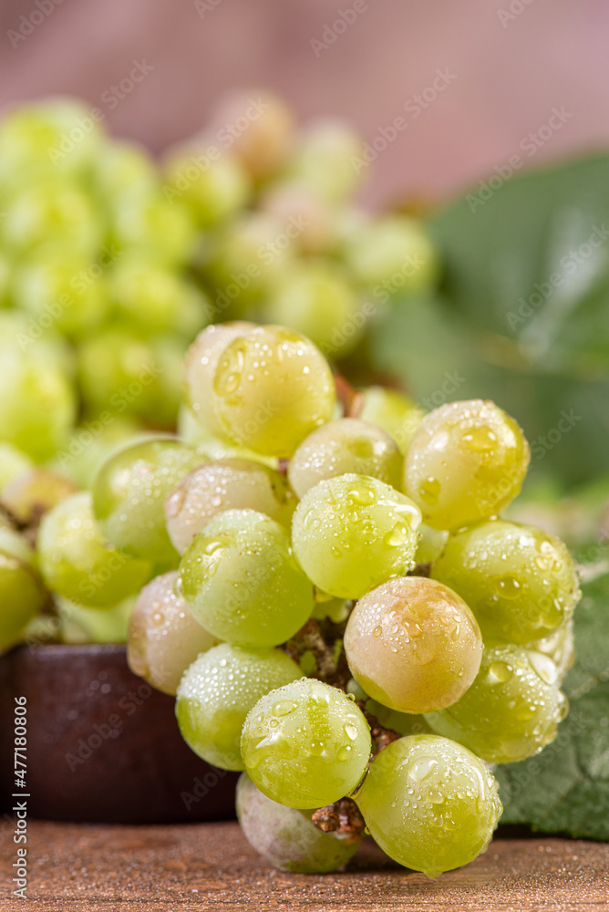 Grapes, bunches of green grapes placed together with a straw basket on wooden surface, selective focus. Grapes, bunches of green grapes placed together with a straw basket on wooden surface, selective focus.