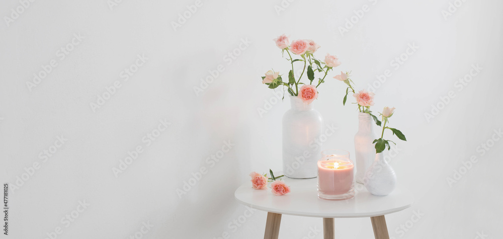 pink roses in white vase on  table on background white wall
