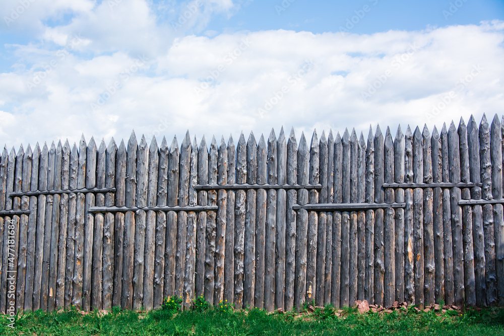 An old wooden fence made of sharp stakes in a Russian Siberian village