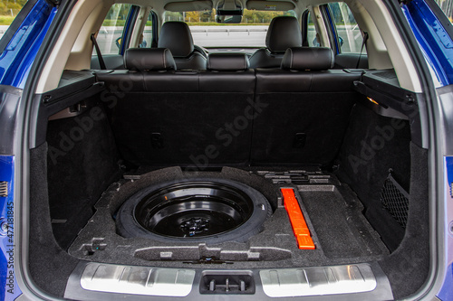 Spare wheel in the trunk of a modern car. Jack lifting and a spare tire in rear of car. © Roman