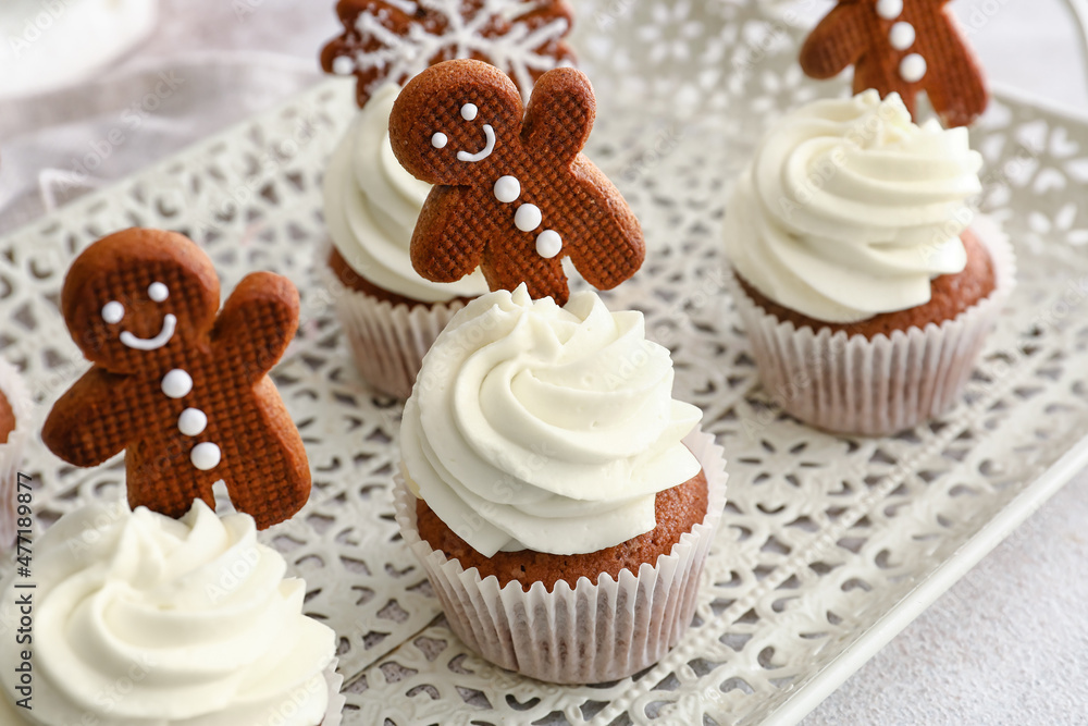 Tray of tasty Christmas cupcakes with gingerbread cookies on light background, closeup Tray of tasty Christmas cupcakes with gingerbread cookies on light background, closeup