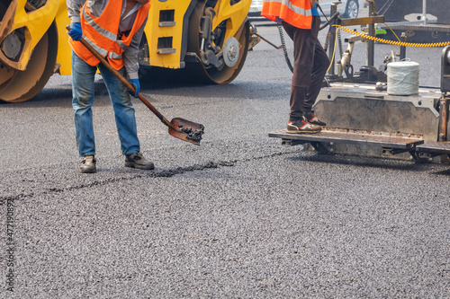 Fotografi Road workers pave fresh asphalt using a shovel, paver and vibratory roller