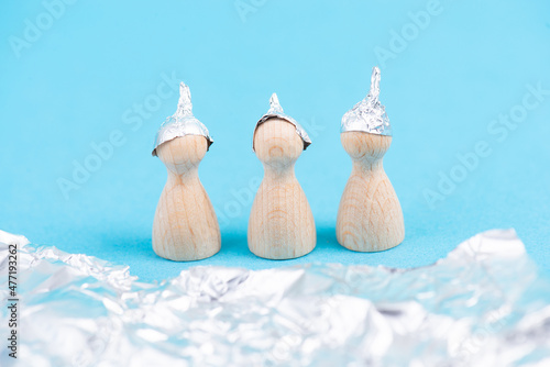 Three wooden figures wearing an alu hat, conspiracy theories, tin foil, symbolic photo