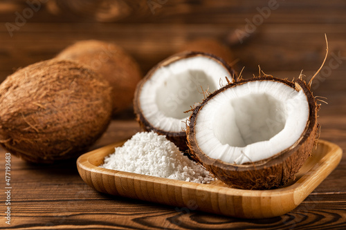 coconut flakes with coconut on a wooden plate on a wooden background. Close-up.