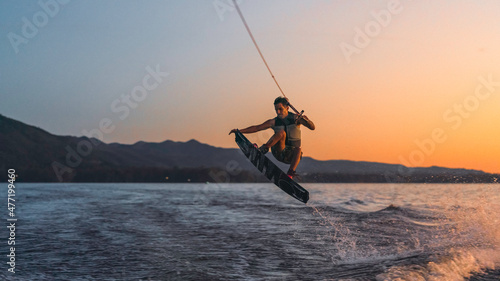 latino mas doing wakeboarding in a lake with mountains in the background