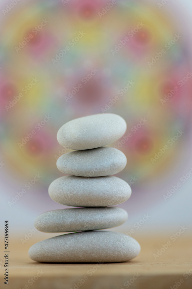 Stone cairn on white and colorfull red yellow mandala background, five stones tower, simple poise stones Stone cairn on white and colorfull red yellow mandala background, five stones tower, simple poise stones