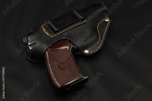 Pistol in leather holster on the black table