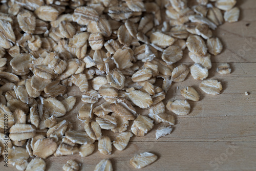 closeup of thick rolled oats scattered on a light wooden surface
