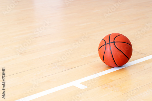 Basketball on hardwood court floor with natural lighting. Workout online concept. Horizontal sport theme poster, greeting cards, headers, website and app