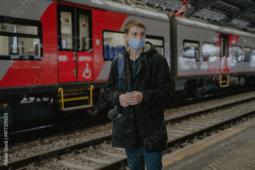 a guy in a mask stands on the platform by the train