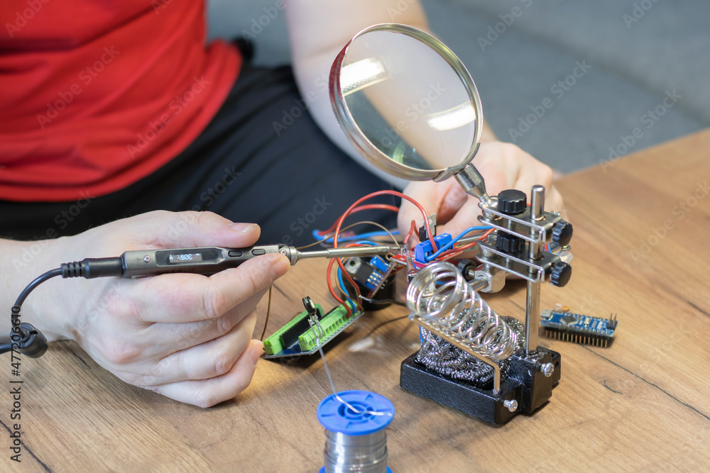 Close-up view of a man's hands using a soldering iron during the repair process.
