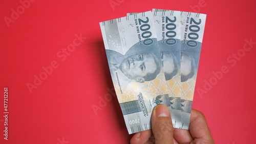 Rupiah the official currency of Indonesia. Business and finance concept. Uang 2000 Rupiah. Red Background. Bank Indonesia, Uang rupiah.