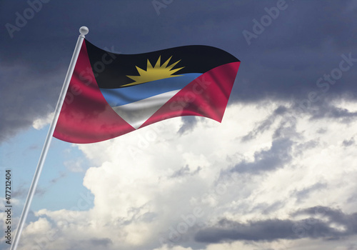 Flag of the Antigua and Barbuda on a stick, dark clouds in the background © Milan