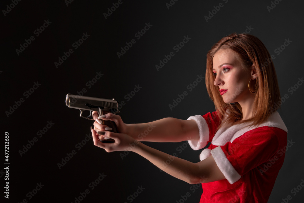 Dangerous bad Santa woman holding gun with evil smile looking at camera. Dangerous bad Santa woman holding gun with evil smile looking at camera.