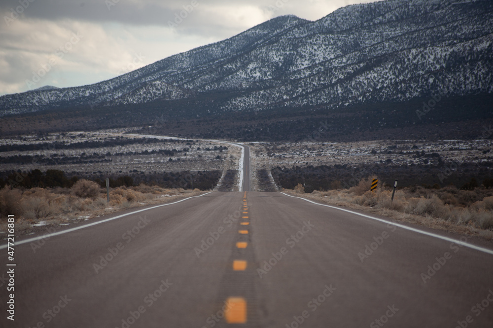 Naklejka premium On an empty stretch of highway , no cars in site. Ahead you can see the snowy mountains.
