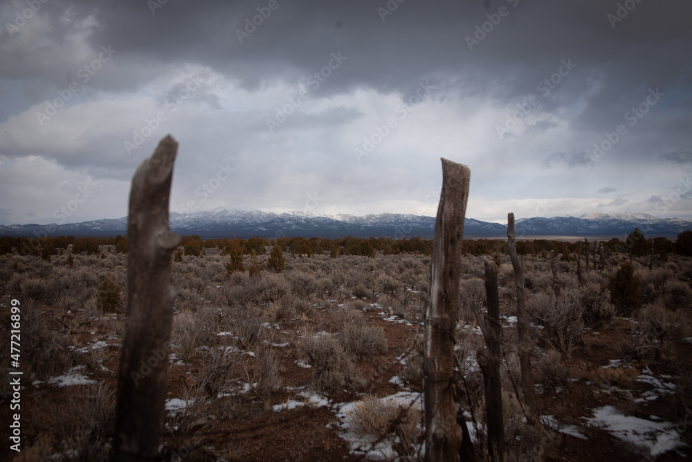 A closer look near the fence posts , in the backgrounds the clouds are closing right before it starts to snow. 