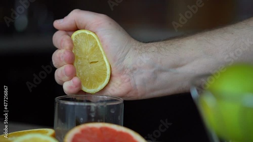 Male hands are squeezing ripe lemon for making citrus juice , healthy lifestyle, fruit juice