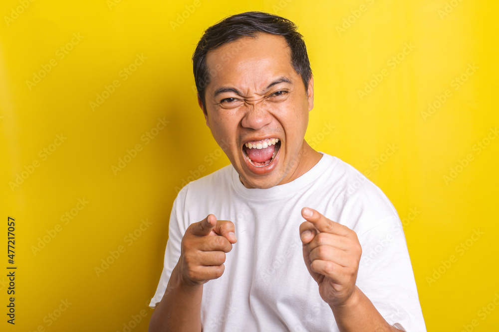 Close-up portrait of cheerful and excited Asian man with both finger pointing to camera isolated on yellow background Close-up portrait of cheerful and excited Asian man with both finger pointing to camera isolated on yellow background