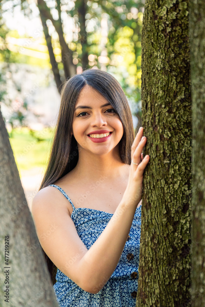 Young woman at park portrait using a dress during summer spring season at a sunny day. Brunette with long black hair.