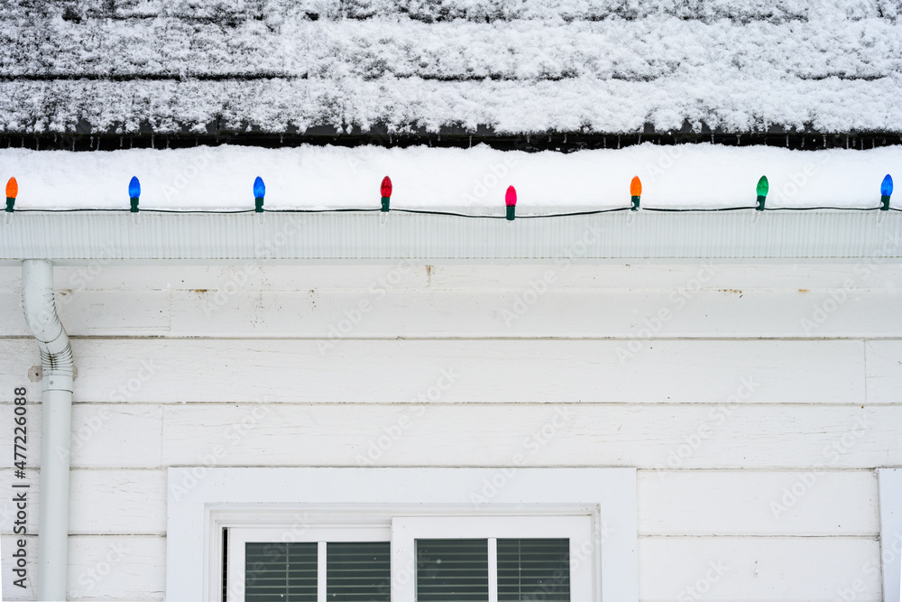 Colorful Christmas lights strung on the edge of a roof with black