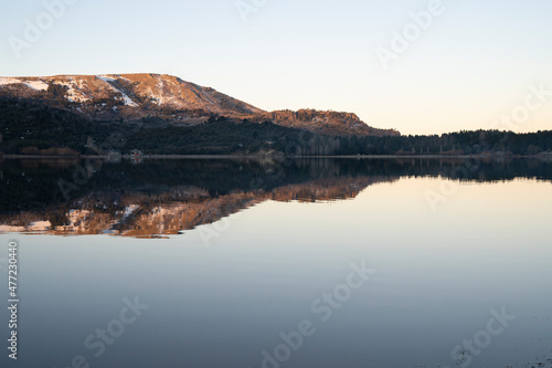 Alpine landscape at nightfall. Magical view of the Andes mountains, forest and lake at sunset. Beautiful symmetrical reflection in the water.