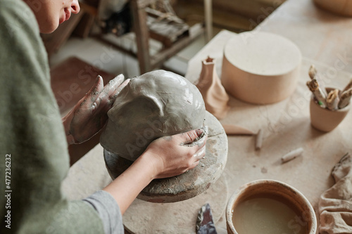 Close-up of designer making sculpture of human face from clay in the ceramic studio photo