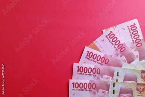 Rupiah the official currency of Indonesia. Business and finance concept. Uang 100000 Rupiah. Bank Indonesia. Red Background, Negative space, Copy space.