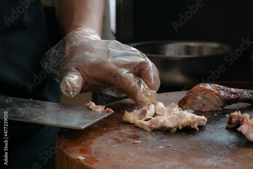 Close up of chef slicing roasted chicken on wooden cutting board. Chef preparing grilled chicken. Dicing chicken meat. photo