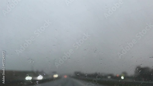 Close-up of windshield wiper on and water drops run down from front window car during rain photo
