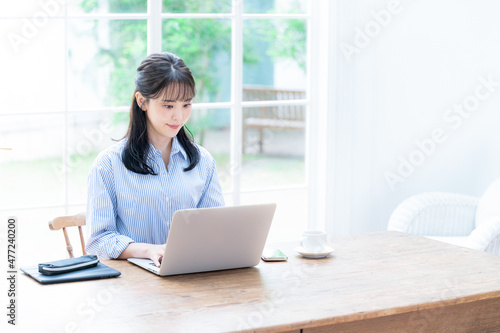 Beautiful Japanese woman working on computer with her head down, copy space available, wide angle, overhead view.