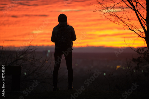 Dark silhouette of a lonely woman enjoying sunset view in evening nature. Loneliness and solitude concept