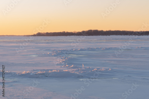 On the snowy bank of the river landscape. Winter snow scene. Winter river in the snow. Hummocks. A pile of ice fragments.