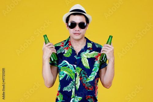 Young Asian boy in summer casual and hat enjoy drinking favorite tasty alcoholic beverage from glass bottle