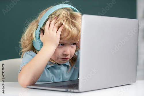 Foto Angry sad school kid working in computer class