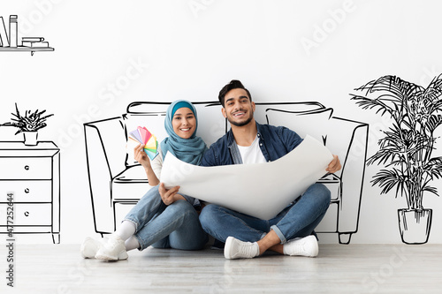 Dreamy arab husband and wife in hijab planning house interior photo