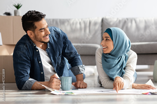 Creative muslim couple laying on floor with apartment scheme photo