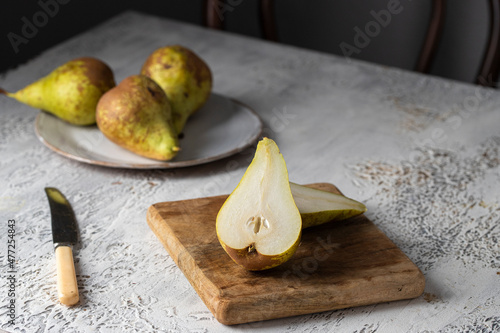 Fresh conference pears  cut in half on cwooden cut board on white table. photo