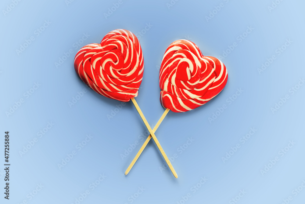 Two crossed red heart lollipops on blue background love and Valentine day background Two crossed red heart lollipops on blue background love and Valentine day background