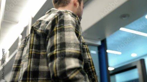 Handheld, young guy rides the subway and reads a book, a student goes to study at the university, morning on the public transport, the guy gets off the train. photo