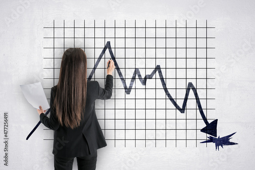 Back view of businesswoman drawing abstract downward falling into hole business chart arrow sketch on concrete wall grid background Fototapeta