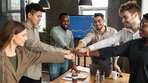 Diverse business people giving fist bump in circle at office