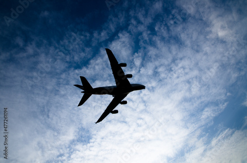Silhouette of an airplane flying isolated on cloudy sky day background.