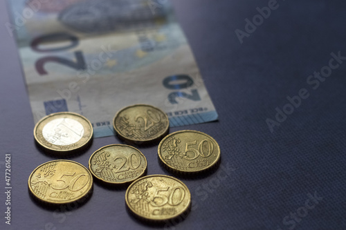 Twenty euro and coins are lying on blue background. Selective focus