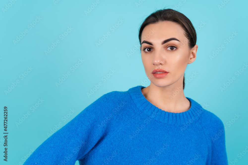 Beauty portrait of a young woman in a blue knitted sweater and natural day makeup, confidently looking at the camera Beauty portrait of a young woman in a blue knitted sweater and natural day makeup, confidently looking at the camera