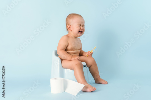 A small child is sitting on a potty and crying. Diarrhea and bloating in a newborn.