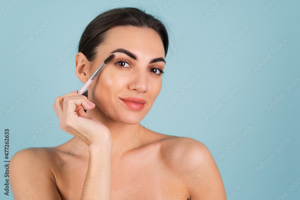 Close up beauty portrait of a woman with perfect skin and natural makeup, full nude lips, holding an eyebrow brush Close up beauty portrait of a woman with perfect skin and natural makeup, full nude lips, holding an eyebrow brush