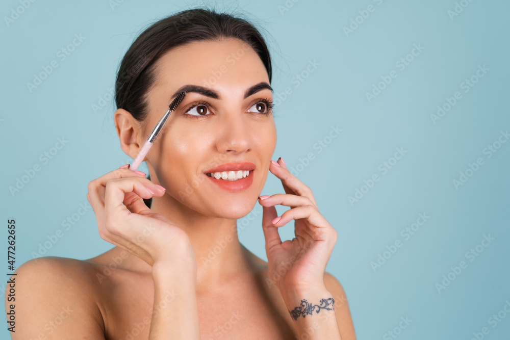 Close up beauty portrait of a woman with perfect skin and natural makeup, full nude lips, holding an eyebrow brush Close up beauty portrait of a woman with perfect skin and natural makeup, full nude lips, holding an eyebrow brush