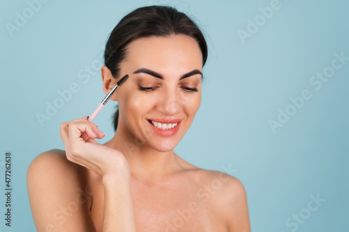 Close up beauty portrait of a woman with perfect skin and natural makeup, full nude lips, holding an eyebrow brush