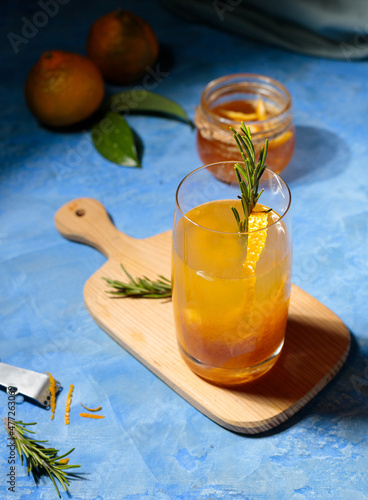 Citrus tea with yuzu zest in a glass and fruit on the table on blue background. Contrast frame, hard shadows.